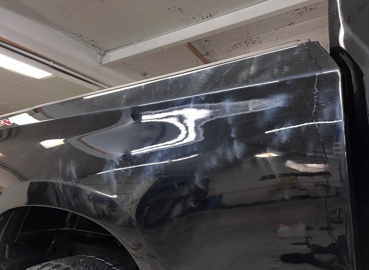 Black truck paint before paint correction showing haze and swirls